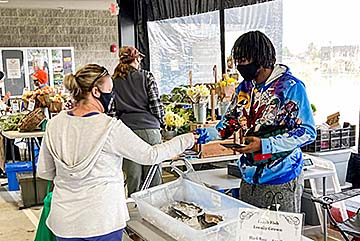 A farmers market customer interacts with a Lincoln University representative at Lincoln's vendor stand.