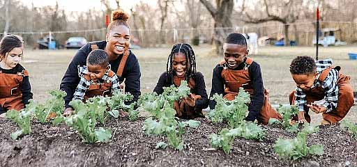 Woman and children gathered around a garden.