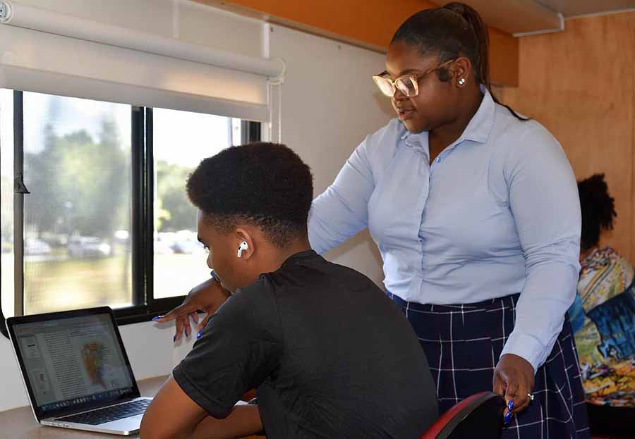 Staff member helping a youth on the computer.