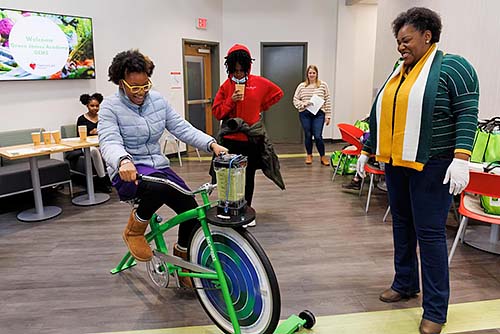 Nicole Swinson watches as a seventh grader rides on the Nutribike to make a smoothie.