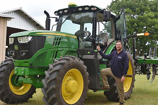 Zachary Jordan standing next to a tractor.