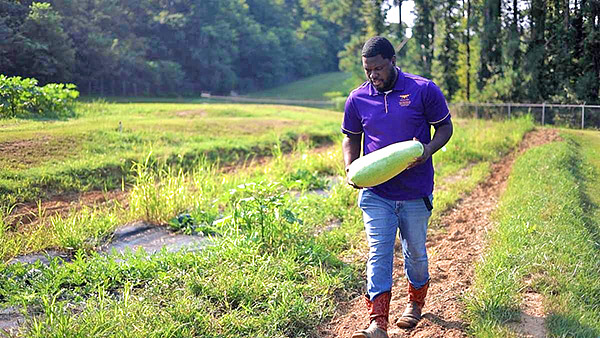 Alcorn student holds a watermelon while in the field.