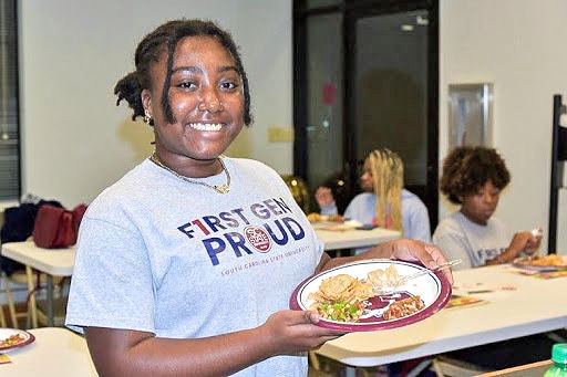 Student holds a plate of food.