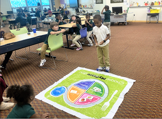 Westwood Elementary School students learn about food on an enlarged My Plate floor diagram.