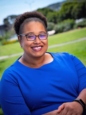 Dr. Willette Crawford smiling with the green landscape behind her.