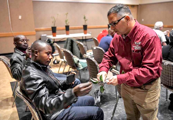 UMES Extension horticulturist Dr. Naveen Kumar Dixit shows Humphrey Nj I Tuma how to obtain a bud from a scion for budding onto a rootstock.