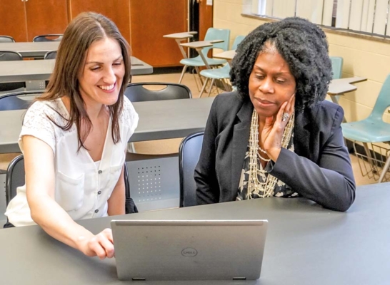 Drs. Meredith Adkins and Marilyn Bailey work on a laptop.