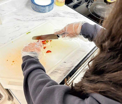 Student uses a knife to chop vegetables.