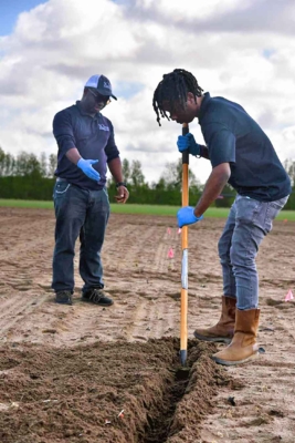 Two people digging in the ground.