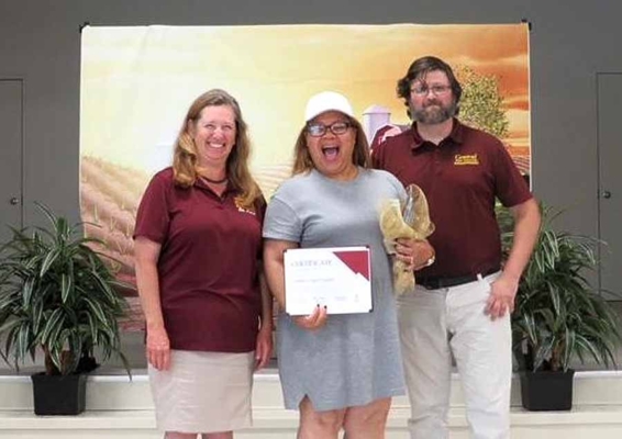 Tamiko Troutman smiles while holding a certificate with two Central State University staff.