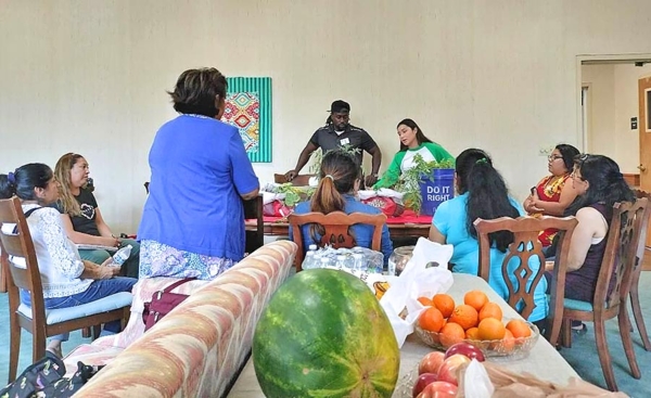 People gather together at a table with fruit.