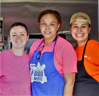 Three volunteers distribute food to families.