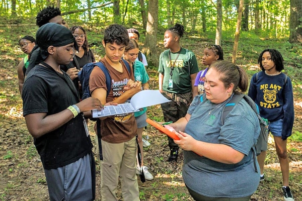 Kaitlynn Gootee collects data with high school campers on a hike.