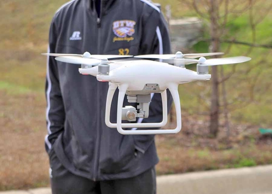 Flying drone with a person behind it.