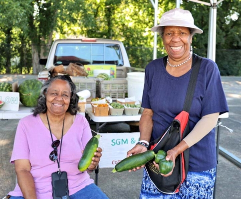 Residents purchasing fresh vegetables at farmers market.