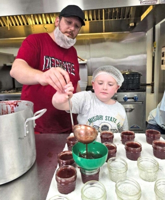 Chef Josh assisting youth in ladling wild plumb jam.