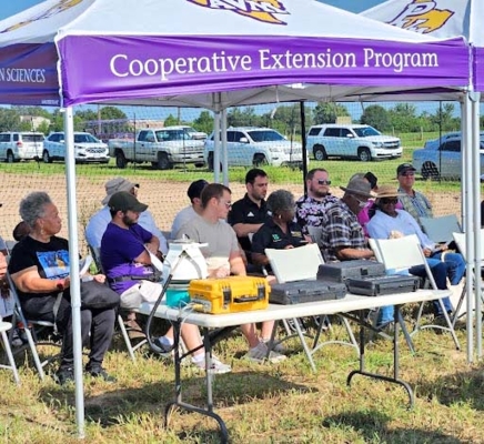 Group sitting outside under a tent.
