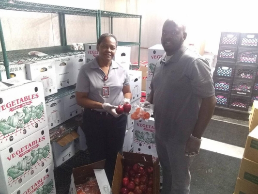 Two people in a food pantry holding fresh produce.