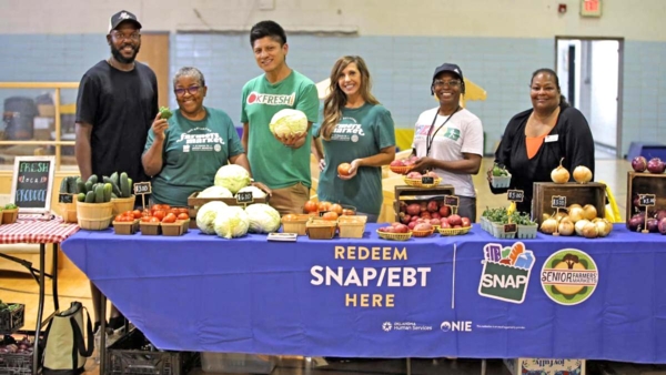 Group behind a table of fresh produce.