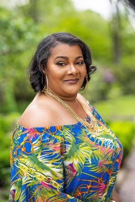 Carolyn Grier smiles at the camera with a green landscape behind her.