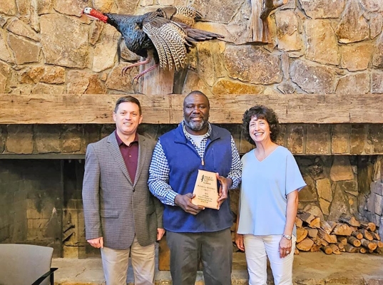 Man holding award with two individuals.