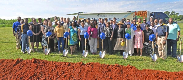 Group stands behind shovels and helmets at breaking ground site.