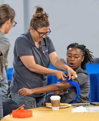 Crystal Cook-Marshall, Ph.D., instructs Taylor Marshall on how to correctly apply a tourniquet.