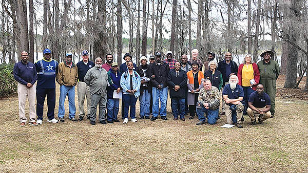 Group poses for a picture with trees in the background.