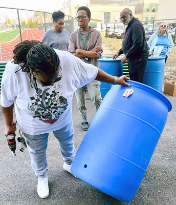 Workshop participant drills a hole in her rain barrel to install the spigot.