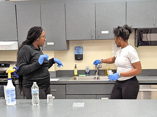 Volunteers film training video at a sink.